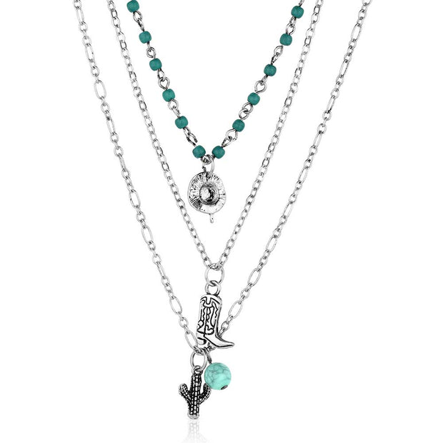 Layered necklace with turquoise beads and charms on a white background
