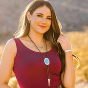 Woman wearing a red top and necklace with a blue pendant outdoors