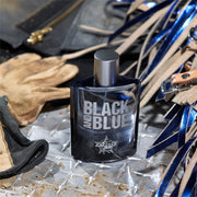 Black and Blue perfume bottle on a textured surface with leather and metal objects.