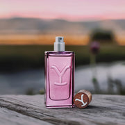 Pink perfume bottle with wooden cap on a wooden surface with a blurred natural background