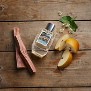 Perfume bottle with cinnamon stick and apples on a wooden surface