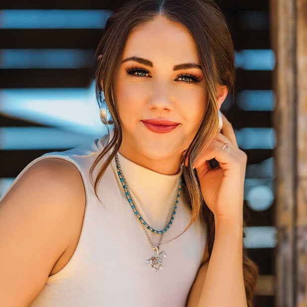 Woman wearing a necklace with a pendant against a blurred background