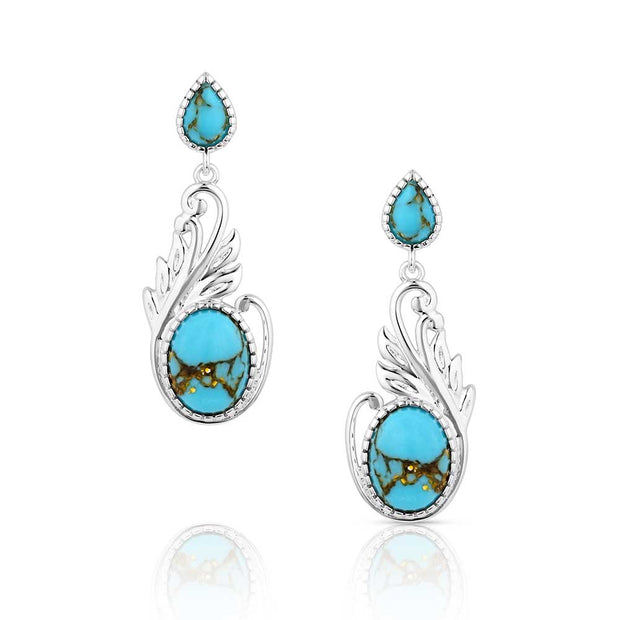 Turquoise earrings with silver wing-like designs on a white background