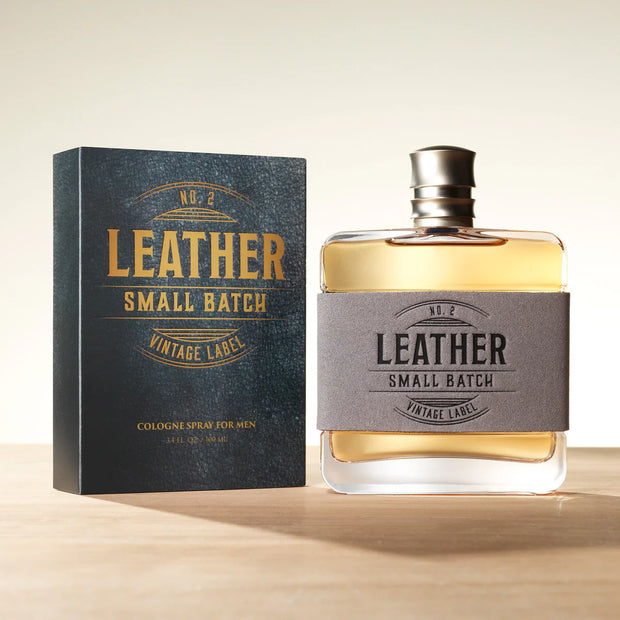 Bottle and packaging of 'Leather Small Batch' cologne on a wooden surface with a light background
