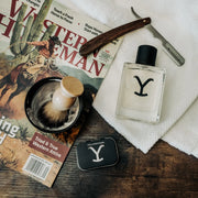 Shaving accessories including a bottle labeled 'Y', a razor, and a brush on a magazine with a Western theme.