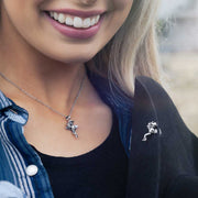 Woman wearing a silver necklace and brooch with a blurred natural background