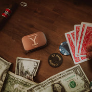 Casino table with money, cards, and a Yuma Rodeo tin on a wooden surface.