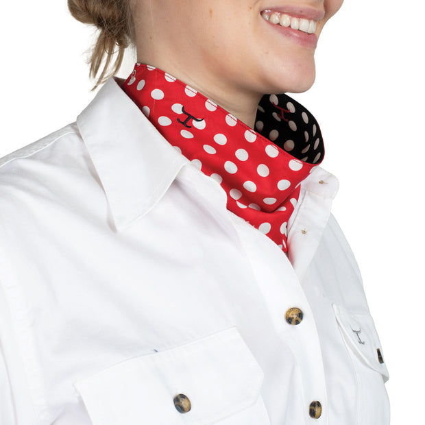 Person wearing a white shirt with a black and red polka dot scarf.