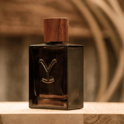 Dark glass perfume bottle with wooden cap on a blurred background