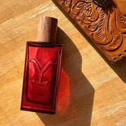 Red perfume bottle with wooden cap on a wooden surface