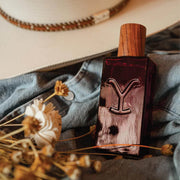 Perfume bottle with wooden cap on denim fabric with dried flowers