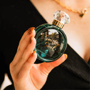 Hand holding a green perfume bottle labeled 'Southern Soul' against a blurred background