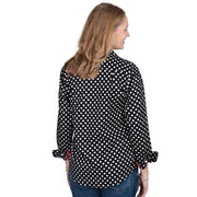 Woman wearing a black polka dot shirt with red cuffs and trim on a white background