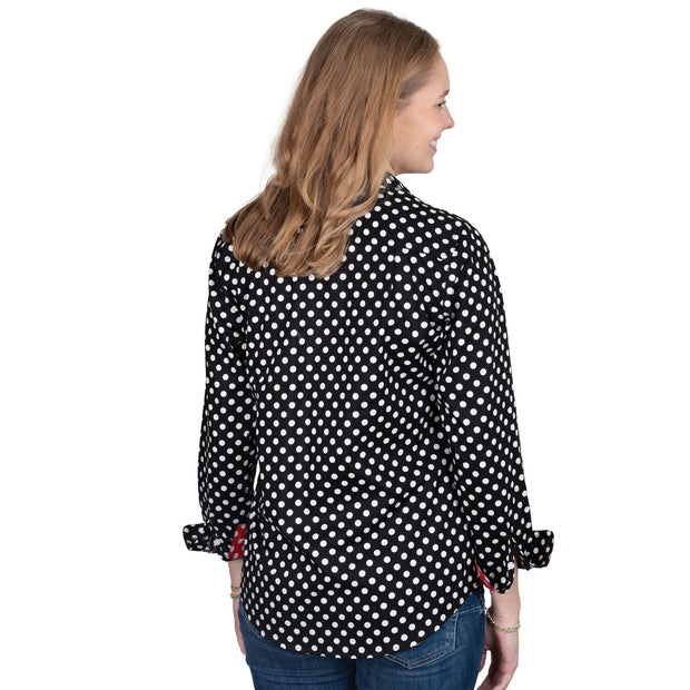 Woman wearing a black polka dot shirt with red cuffs and trim on a white background