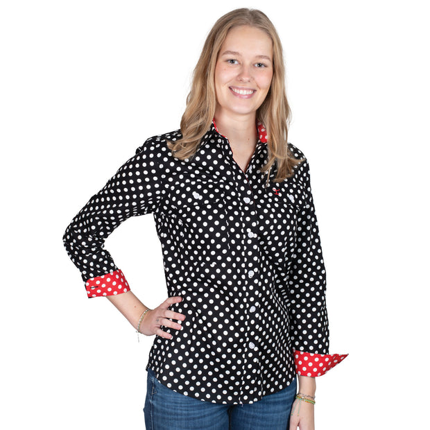 Woman wearing a black polka dot shirt with red cuffs and trim on a white background