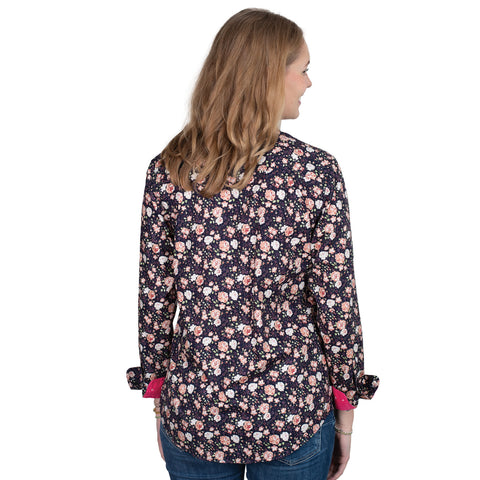Woman wearing a floral patterned shirt with pink accents on a white background