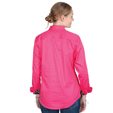 Woman wearing a bright pink shirt with floral cuffs on a white background