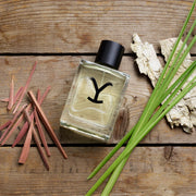 Perfume bottle with a 'Y' logo on a wooden surface with natural elements
